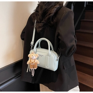 Close-up of light blue leather bowling bag with cute bear charm and HIKAXIQI branding