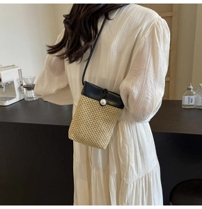 Detail of straw woven crossbody bag with black leather flap and pearl closure