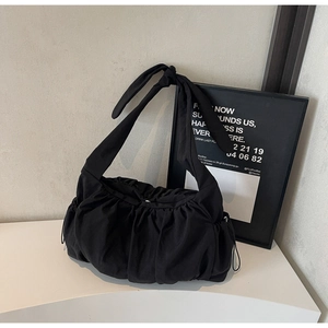 Close-up of black pleated nylon tote bag featuring a decorative knotted shoulder strap