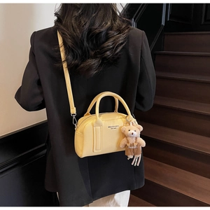Detail of yellow lychee grain leather Boston bag with a cute bear plush pendant