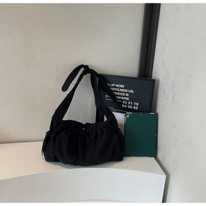 Black nylon tote bag featuring gathered pleats and a large bow detail on the shoulder strap