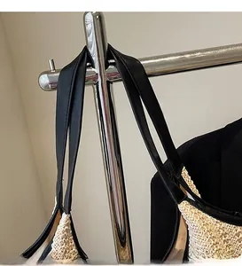 Detail of smooth black leather shoulder strap on a woven minimalist straw tote bag