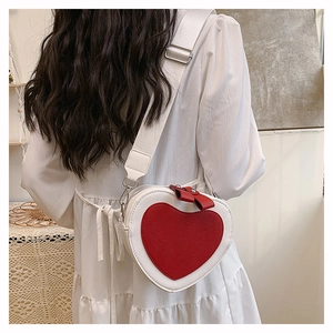 Model view of heart-shaped crossbody bag in white and red with bow detail and strap