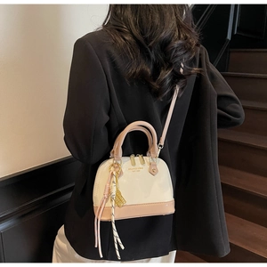 Detail view of stylish shell handbag with dual top handles and detachable shoulder strap