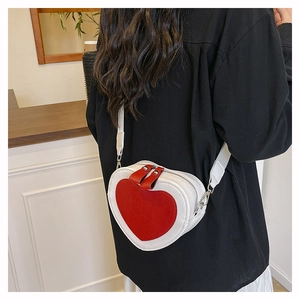 Detail view of heart-shaped crossbody bag with red leather patch and wide shoulder strap