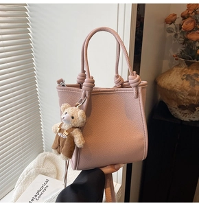 Pink lychee grain leather bucket bag featuring a knot handle and cute bear charm