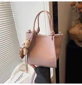 Detailed shot of pink lychee texture bucket bag with cute plush bear charm decoration
