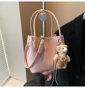 Detail of light pink bucket bag with lychee pattern and a cute teddy bear pendant