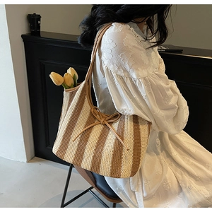 Detail of striped woven tote bag with leather bow and long shoulder straps