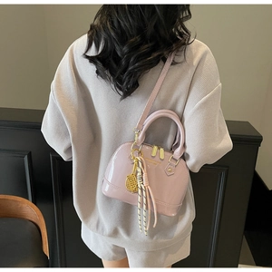 Close-up of lavender shell handbag in glossy patent leather with gold tennis racket charm