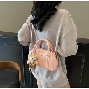 Detail of pink bowling bag with lychee texture and cute bear charm on model shoulder
