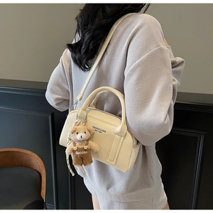 Close-up of cream bowling bag with lychee texture and cute plush bear charm