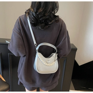 Zilveren metallic halve maan tas met parelketting en hartlogo als crossbody gedragen