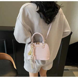 Detail of light purple patent leather shell bag with gold hardware and tassel accents
