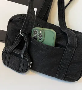 Dettaglio borsa tote in denim nero con ampia tasca frontale e mini pochette coordinata