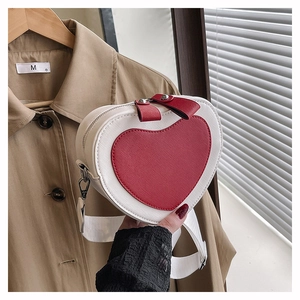 Detailed close-up of a heart-shaped crossbody bag with red and white contrast stitching