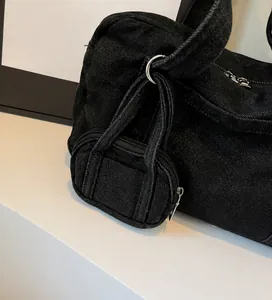 Dettaglio del tessuto in denim nero lavato con un elegante mini astuccio con cerniera