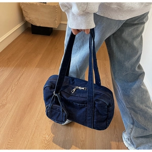 Dettaglio borsa a spalla in denim blu scuro con mini ciondolo e cerniera in metallo argento