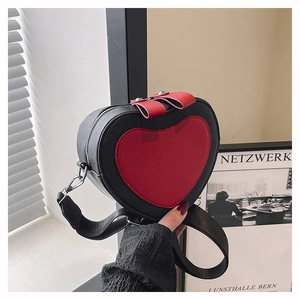 Detail of heart-shaped crossbody bag with red bows and wide fabric shoulder strap