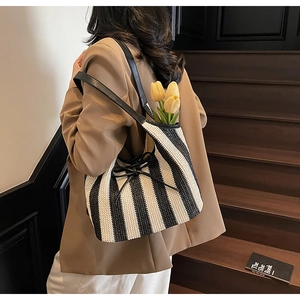 Detail of bohemian black and white striped woven tote bag with a black leather bow