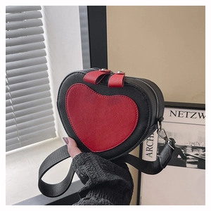 Detail of heart-shaped crossbody phone bag with black textured leather and red accent