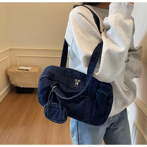 Dettaglio della borsa a tracolla cilindrica in denim blu con mini portamonete coordinato