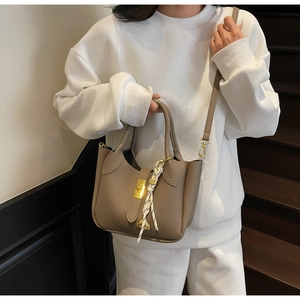 Dettaglio borsa a secchiello in pelle grigio elefante con chiusura oro e nastro twilly