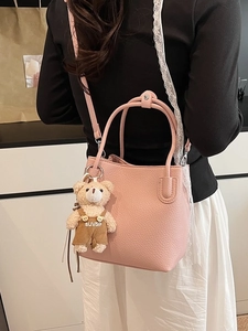 Minimalist pink leather bucket bag with cute plush bear charm on a female model