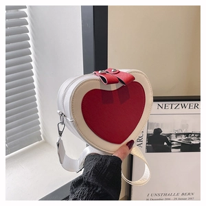 Close-up of heart-shaped crossbody bag with red and white color blocking and litchi texture