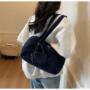 Dettaglio borsa tote in denim blu con tracolla larga e mini custodia accessoria coordinata