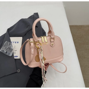Pink patent leather shell bag with gold zippers and decorative tennis racket keychain
