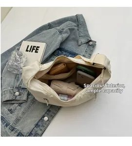 Spacious interior of beige canvas dumpling bag holding an umbrella and phone