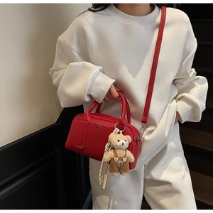Detail of red pebbled leather bowling bag with cute teddy bear charm and logo print