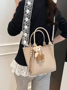 Minimalist apricot tote bag with floral lace strap and bear charm shown on a model