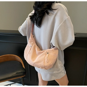 Detail of peach nylon crescent bag featuring functional double front zipper pockets