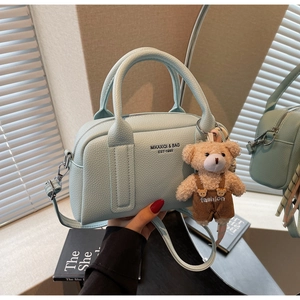 Detail of light blue Boston bag with lychee texture and cute teddy bear pendant