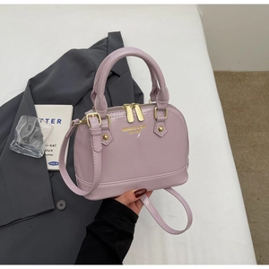 Detail of light purple patent leather shell bag with gold hardware and logo lettering