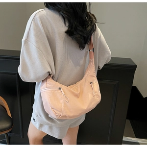 Detail of light pink crescent bag showing water-resistant nylon texture and dual zippers