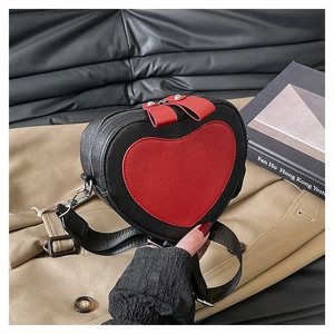 Detail of heart-shaped crossbody bag with red bow zippers on a trench coat