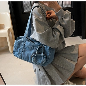 Dettaglio borsa a cilindro in denim blu con mini charm e tracolla per uno stile casual