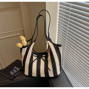 Detail of black and white striped woven tote bag with a small black bow on a leather sofa