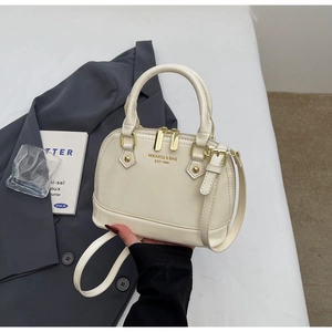 Close-up of cream shell handbag with gold hardware and removable shoulder strap