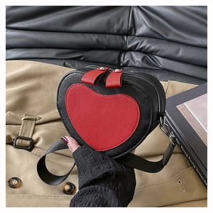 Detailed view of heart-shaped crossbody bag featuring red and black contrast textured leather