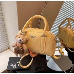 Detail view of yellow bowling bag with lychee texture leather and cute bear charm