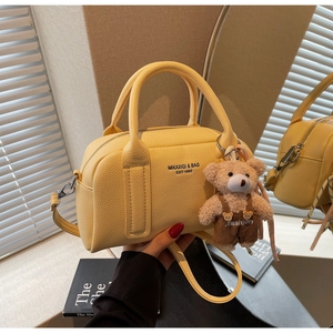 Detail of yellow lychee grain leather bowling bag with cute bear charm and text detail