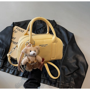 Detail of yellow lychee textured bowling bag with cute plush bear charm and logo print