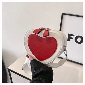 Detail view of heart-shaped crossbody bag with red pattern and white adjustable strap