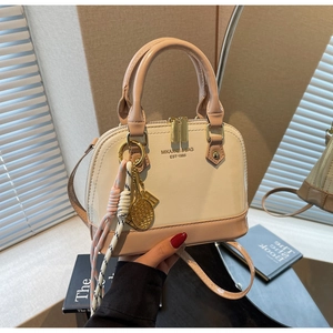 Detail of shell-shaped handbag with golden double zippers and tennis racket charm