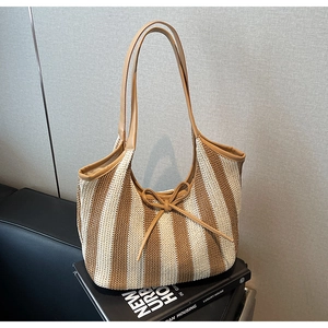 Detail of striped woven tote bag with brown faux leather straps and ribbon decoration