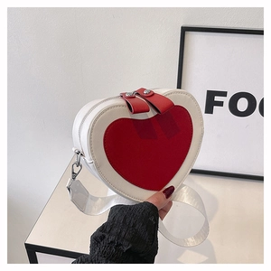 Detail view of heart-shaped crossbody bag featuring red and white leather and dual zippers